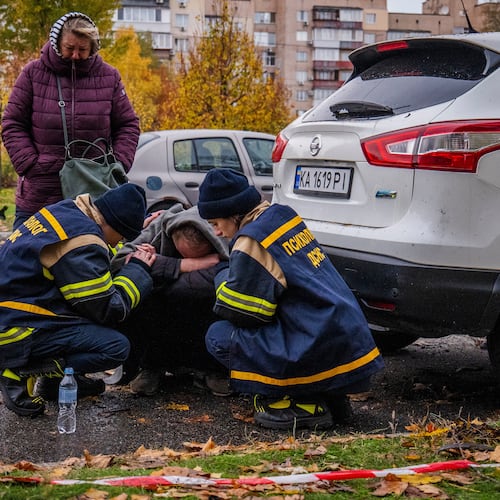 Emergency workers comfort a man who lost his son in Russia's drone attack that hit residential buildings in Kyiv, Ukraine, Sunday, Oct. 26, 2025. (AP Photo/Dan Bashakov)