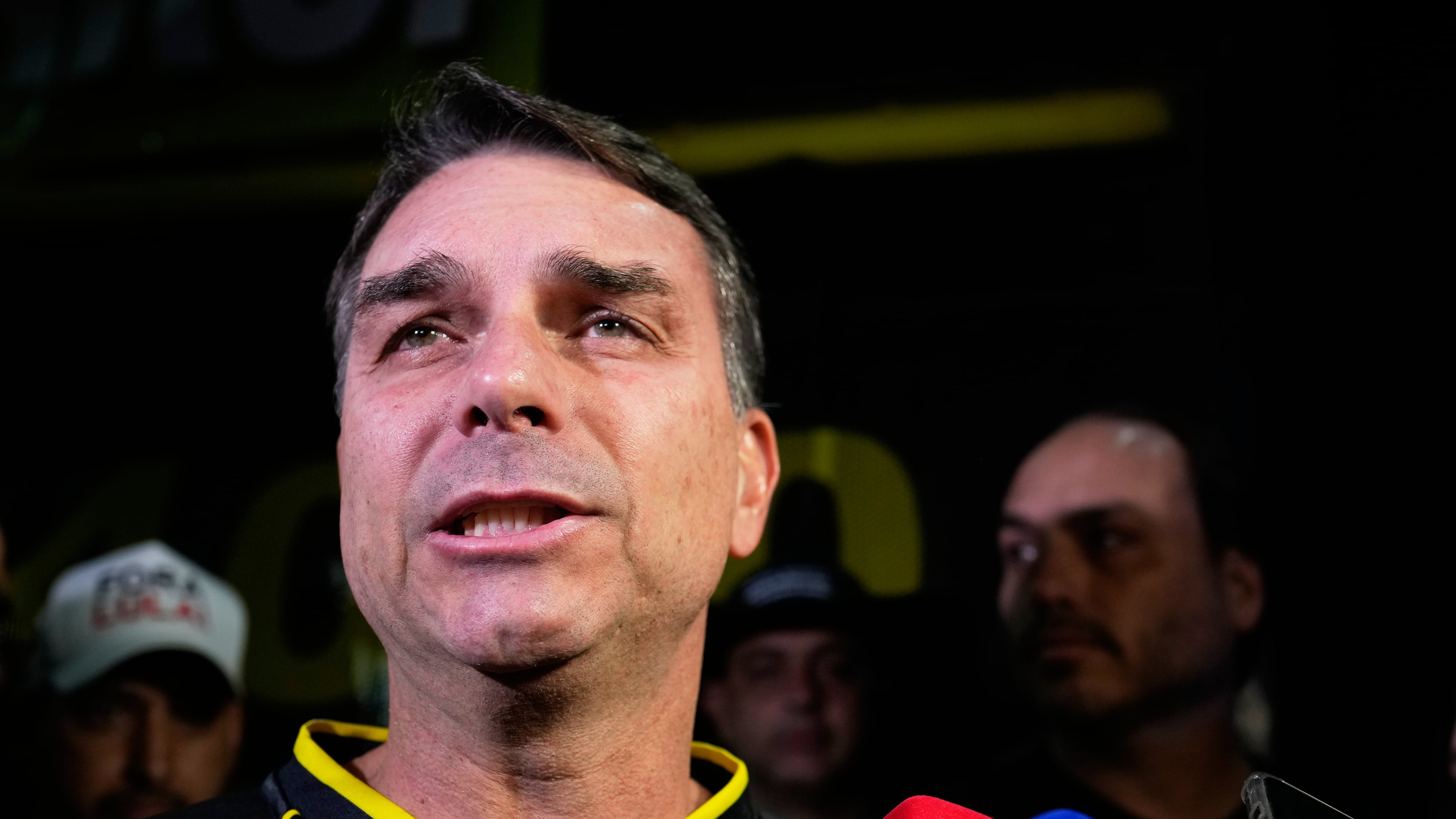 Flavio Bolsonaro, son of ex-President Jair Bolsonaro, speaks during a vigil outside the former president's residence in Brasília, Brazil, Saturday, Nov. 22, 2025, after his father's arrest earlier in the day, carried out days before he was set to start serving his 27-year sentence for leading a coup attempt. (AP Photo/Eraldo Peres)