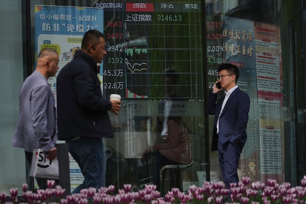 People walk by an electronic board displaying Shanghai shares trading index at a brokerage house, in Beijing, Monday, April 7, 2025. (AP Photo/Andy Wong)