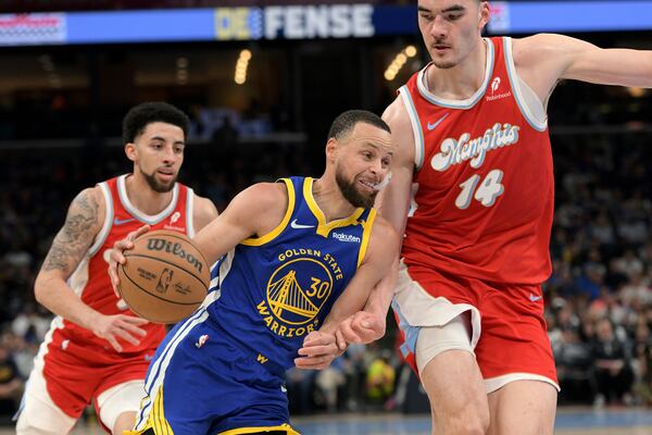 Golden State Warriors guard Stephen Curry (30) drives between Memphis Grizzlies center Zach Edey (14) and guard Scotty Pippen Jr., left, in the first half of an NBA basketball game, Tuesday, April 1, 2025, in Memphis, Tenn. (AP Photo/Brandon Dill)