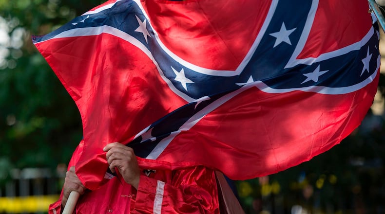 This July 8, 2017, photo shows a member of the Ku Klux Klan holding a Confederate flag over his face during a rally, calling for the protection of Southern Confederate monuments, in Charlottesville, Va. On Sept. 1, 2017, wearing the Confederate flag became a violation of the Lapel (Ind.) High School dress code after students wore the flag two days in a row.