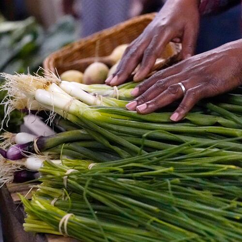 FILE - A farmer rests his hands on vegetables at a market June 15, 2023, in Manchester, N.H. (AP Photo/Charles Krupa, File)