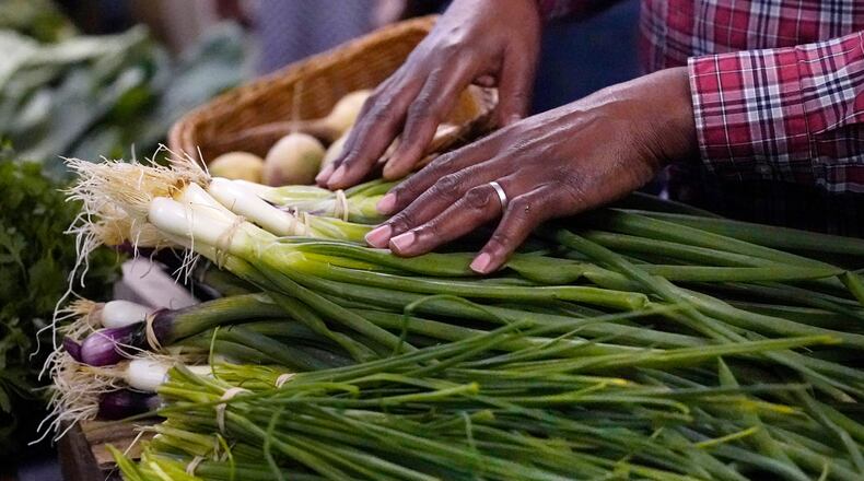 FILE - A farmer rests his hands on vegetables at a market June 15, 2023, in Manchester, N.H. (AP Photo/Charles Krupa, File)