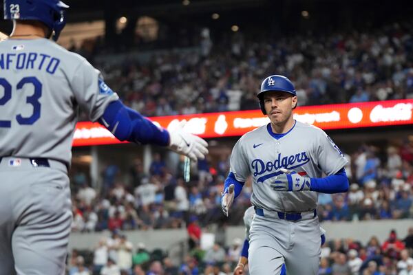 Los Angeles Dodgers' Freddie Freeman is congratulated by Michael Conforto (23) after hitting a two run home run that scored Mookie Betts off of Texas Rangers pitcher Nathan Eovaldi during the fourth inning of a baseball game Saturday, April 19, 2025, in Arlington, Texas. (AP Photo/Jeffrey McWhorter)