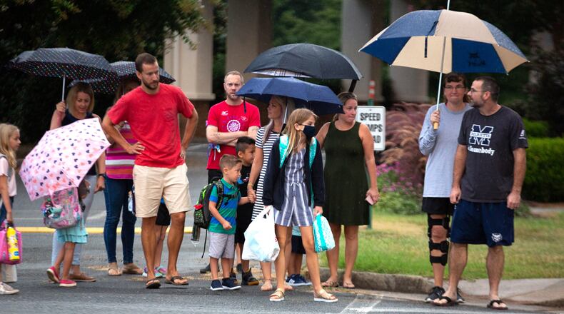 Parents walk their children to the entrance of Woodstock Elementary School in Cherokee County on the first day of school on August 3, 2020. A second-grade class at Sixes Elementary School  in Cherokee will have to quarantine for two weeks after a student tested positive for COVID-19. STEVE SCHAEFER FOR THE ATLANTA JOURNAL-CONSTITUTION