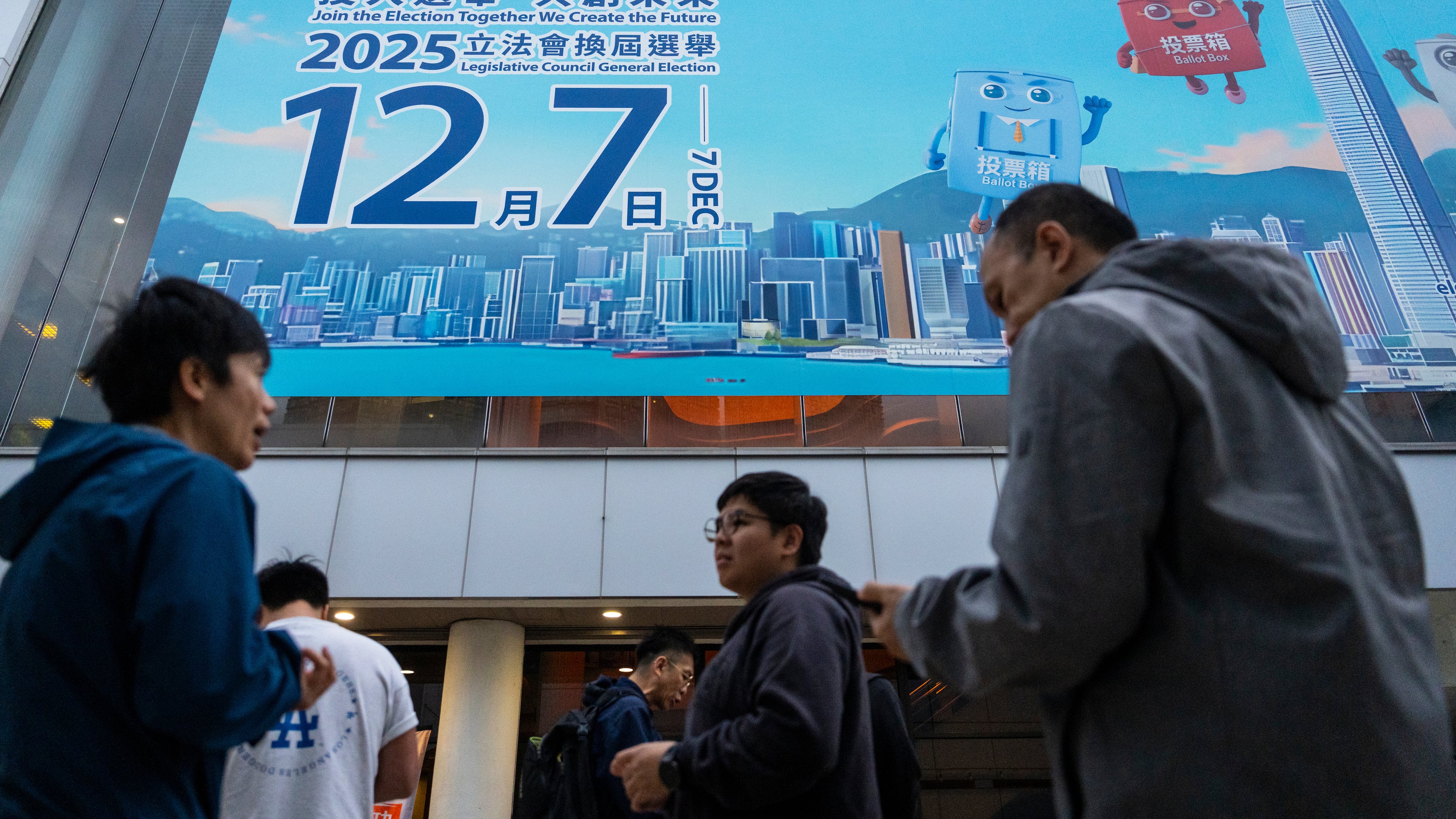 Pedestrians walk past the banner promoting the Hong Kong Legislative Council General Election in Hong Kong on Wednesday, Dec. 3, 2025. (AP Photo/Chan Long Hei)
