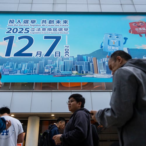 Pedestrians walk past the banner promoting the Hong Kong Legislative Council General Election in Hong Kong on Wednesday, Dec. 3, 2025. (AP Photo/Chan Long Hei)