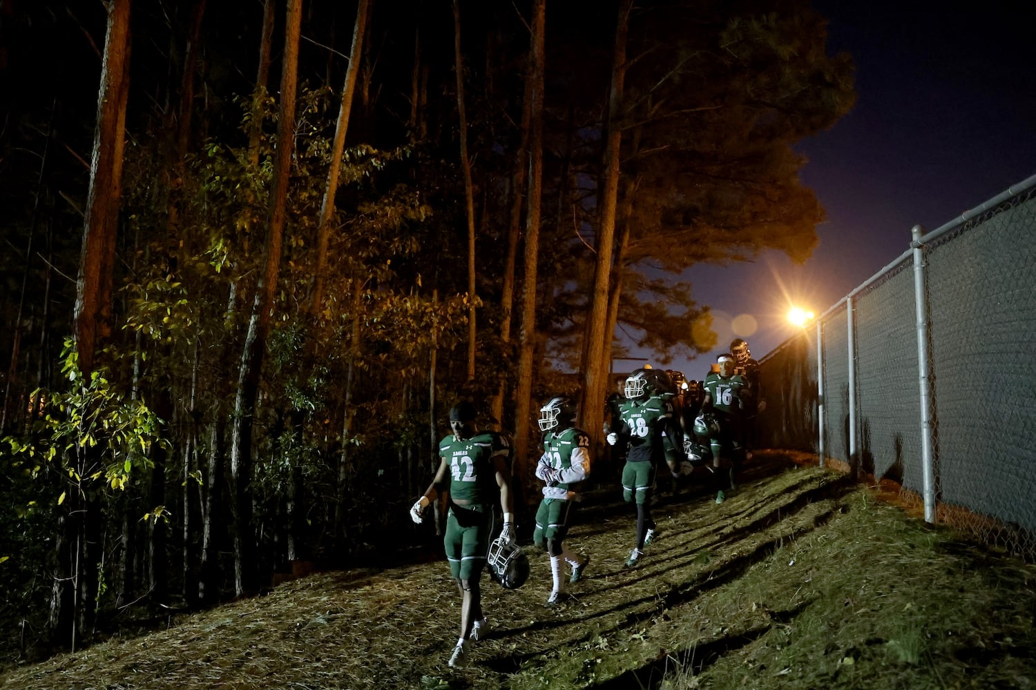 Collins Hill players walk out of the woods on their way to their football stadium before their game against North Gwinnett. JASON GETZ FOR THE ATLANTA JOURNAL-CONSTITUTION
