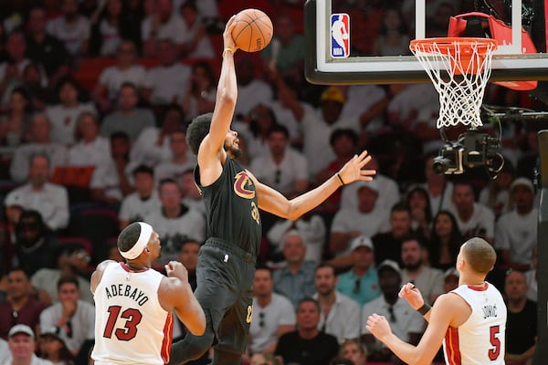 Cleveland Cavaliers center Jarrett Allen dunks between Miami Heat center Bam Adebayo (13) and forward Nikola Jovic (5) during the first half in Game 3 of an NBA basketball first-round playoff series, Saturday, April 26, 2025, in Miami. (AP Photo/Michael Laughlin)
