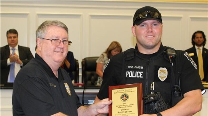 From left, Snellville Police Department Chief Roy Whitehead presents officer Brett Chism with the National Criminal Enforcement Association award for making a bust of 45,000 ecstasy pills at Monday’s Council meeting. Courtesy Snellville