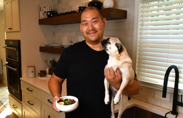 Chef Brian So stands in his Marietta home kitchen with one of his favorite pugs, Freddie. So says his fine-dining restaurant, Spring, quietly reopened in February. (Chris Hunt for the AJC 2023)