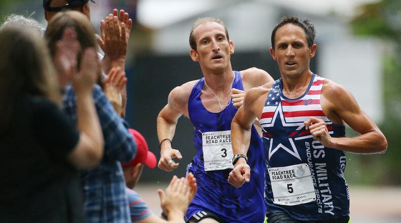 Spectators cheer on the top two finishers in the main wave as they break away from the pack and round a curve on Peachtree Street on their last mile to the finish line in the AJC Peachtree Road Race on Saturday, July 4, 2015, in Atlanta. Curtis Compton / ccompton@ajc.com