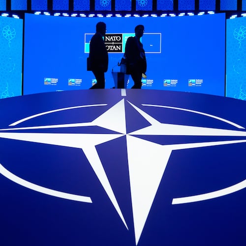 Two men walk past the NATO logo during the NATO Defense Industry Forum at the NATO summit in Ankara, Turkey, Tuesday, July 7, 2026. (AP Photo/Hussein Malla)
