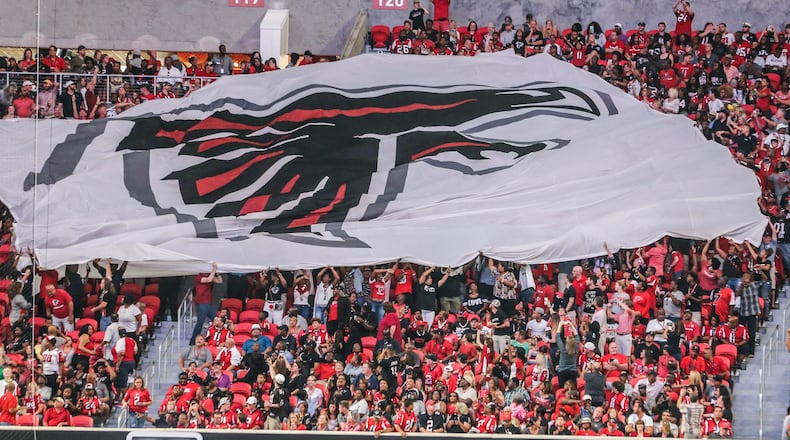 Falcons fans pass a giant flag in the stands during Saturday’s opening game at Mercedes-Benz Stadium.
