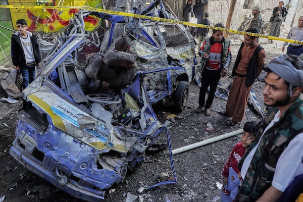 Yemenis watch a damaged vehicle at Farwah popular market which Houthis said it was struck by U.S. airstrikes in Sanaa, Yemen, Monday, April 21, 2025. (AP Photo)
