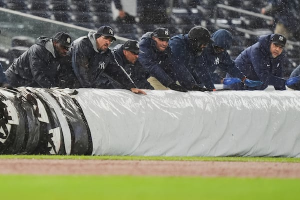 The grounds crew covers the field during the sixth inning of a baseball game between the New York Yankees and the San Francisco Giants Friday, April 11, 2025, in New York. (AP Photo/Frank Franklin II)