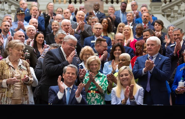 Gov. Brian Kemp (left), seated next to first lady Marty Kemp, signed the state spending plan for the coming fiscal year on Tuesday. 
