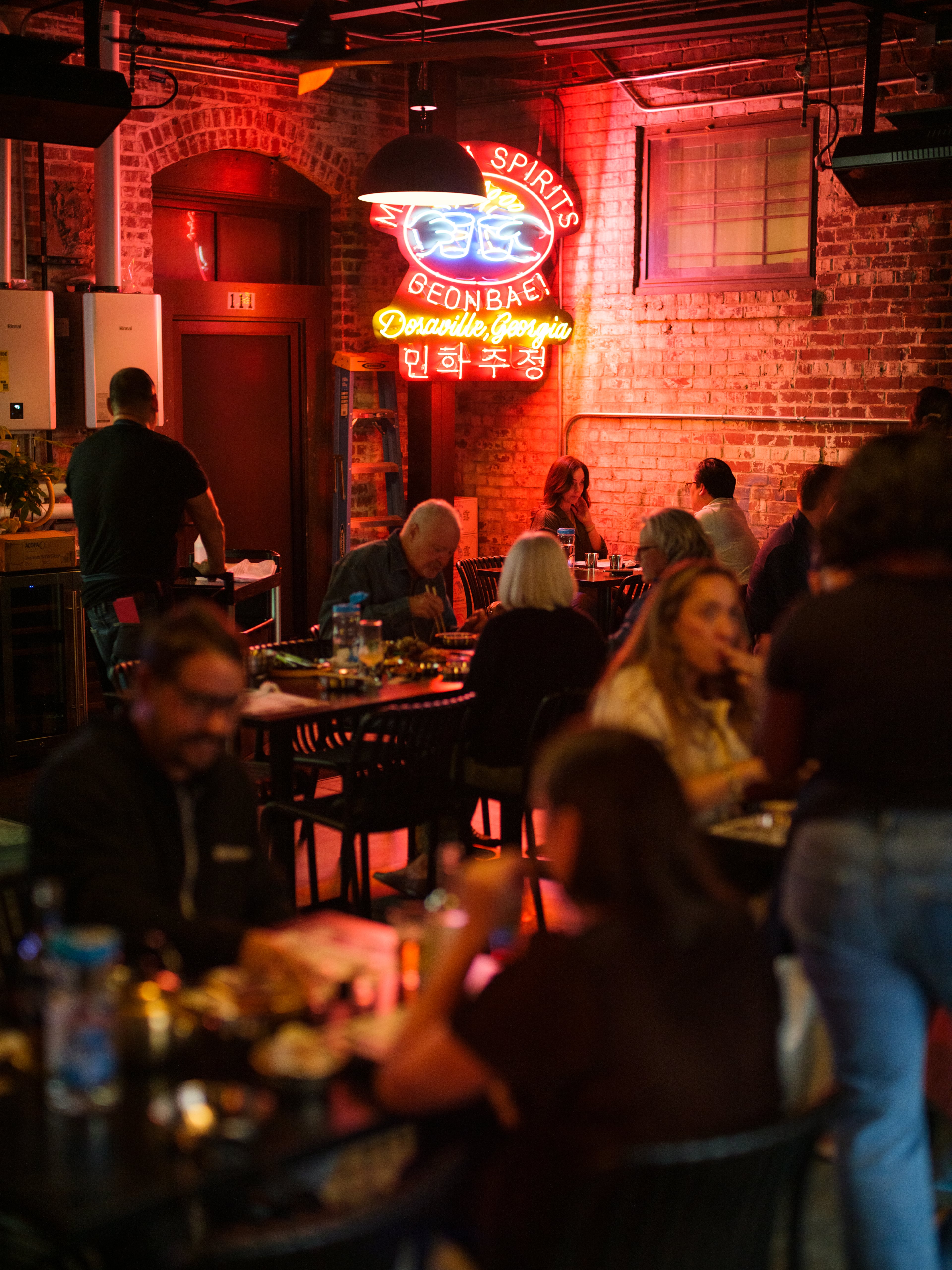 Korean restaurant Spring 2nd Branch's dining room is dimly lit with neon signs and TVs playing Korean music videos. (Courtesy of Peter Ho)