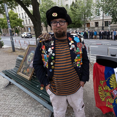A man identified by Polish media as Robert Kuzovkov and by prosecutors as Robert K., in accordance with Polish privacy law, who they said was an artist who used the pseudonym Semyon Skrepetsky, poses for a photo with one of his paintings near the Russian Embassy in Berlin, Germany, on Friday, June 12, 2026, four days before Polish authorities said he was shot and killed in Biala Podlaska, Poland. (Vasily Krestyaninov/SOTA via AP)