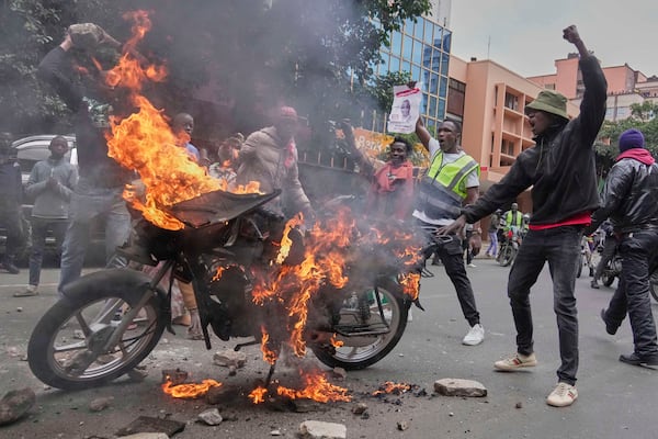 Protesters gesture in-front of a burning motorcycle during a demonstration over the death of blogger Albert Ojwang in police custody, in downtown Nairobi, Kenya, Tuesday, June 17, 2025. (AP Photo/Brian Inganga)