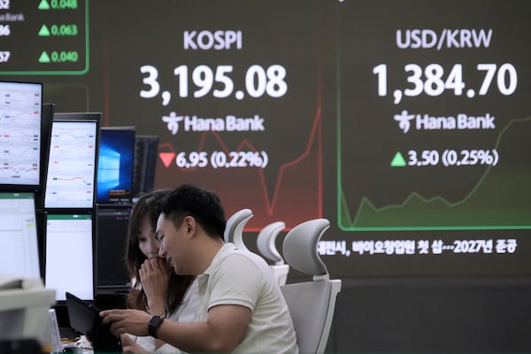 Currency traders work near a screen showing the Korea Composite Stock Price Index (KOSPI) and the foreign exchange rate between U.S. dollar and South Korean won, right, at the foreign exchange dealing room of the Hana Bank headquarters in Seoul, South Korea, Tuesday, July 15, 2025. (AP Photo/Ahn Young-joon)