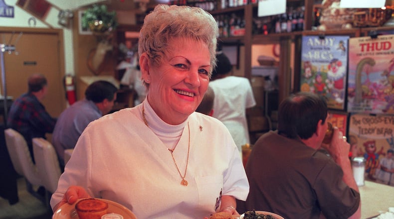 Waitress Carolyn Graham holds a plate of fried chicken, greens and cheese- covered broccoli and another plate of bread at Bobby and June's Kountry Kitchen in Midtown in 1999. / AJC file photo