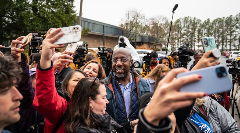 Democratic U.S. Sen. Raphael Warnock poses for selfies with supporters at a canvassing event Tuesday in Norcross. (Nicole Craine/The New York Times)