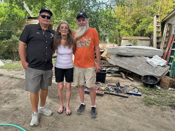 Colleen Lucas, center, and her husband, Dave, right, stand outside their flood-destroyed home in Ingram, Texas, with Lucas' son John Vinyard, on Friday, July 11, 2025. (AP Photo/Gabriela Aoun Angueira)