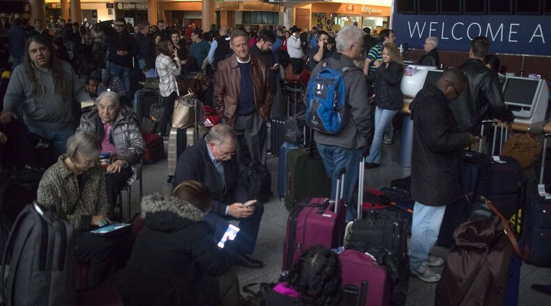 Passengers wait in a dark terminal at Hartsfield-Jackson International Airport Sunday, December 17, 2017. The Airport is reporting a loss of electricity. The FlightAware site reports the airport is currently holding all inbound flights due to an equipment outage. STEVE SCHAEFER / SPECIAL TO THE AJC