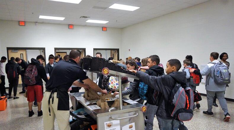Dean Rusk Middle School students check out the offerings on the breakfast cart as school nutrition worker David Bergman restocks the supply of chicken biscuits and sausage biscuits. CHEROKEE COUNTY SCHOOL DISTRICT