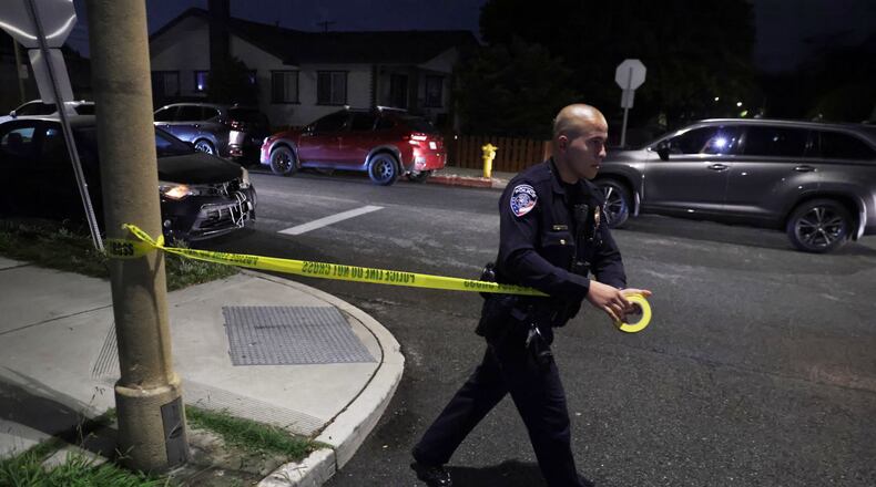 A law enforcement officer sets up police tape near an address connected to Cole Tomas Allen, the shooting suspect at the White House Correspondents Dinner on Saturday, April 25, 2026, in Torrance, Calif. (AP Photo/Ethan Swope)