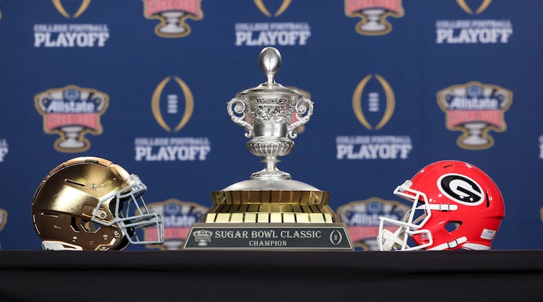 The helmets for Notre Dame and Georgia are shown next to the Sugar Bowl trophy before the joint coach news conference at the Sheraton on Tuesday, Dec. 31, 2024, in New Orleans. (Jason Getz/AJC)