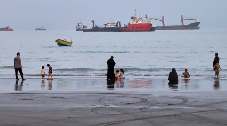 People spend time at a beach as commercial vessels are anchored in the Strait of Hormuz off Bandar Abbas, Iran, Wednesday, Aug. 5, 2026. (Amirhosein Khorgooi/ISNA via AP)
