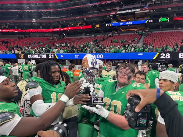 Buford offensive linemen hold up the GHSA football state championship trophy after beating Carrollton 28-21 in the Class 6A state final on Tuesday, Dec. 16, 2025, at Mercedes-Benz Stadium in Atlanta. (Jack Leo/AJC)