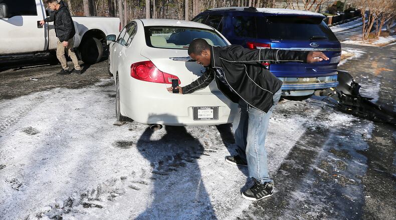 January 8, 2017, Canton: Bobby Wade (left) almost falls on the ice after he lost control of his white Infiniti sliding down a slick hill into a Ford Explorer that had already crashed on Timber Trace Road in the Cherokee Falls Estates at the Lake subdivision on Sunday, Jan. 8, 2017, in Canton. Secondary roads are still a major concern for motorists. Curtis Compton/ccompton@ajc.com