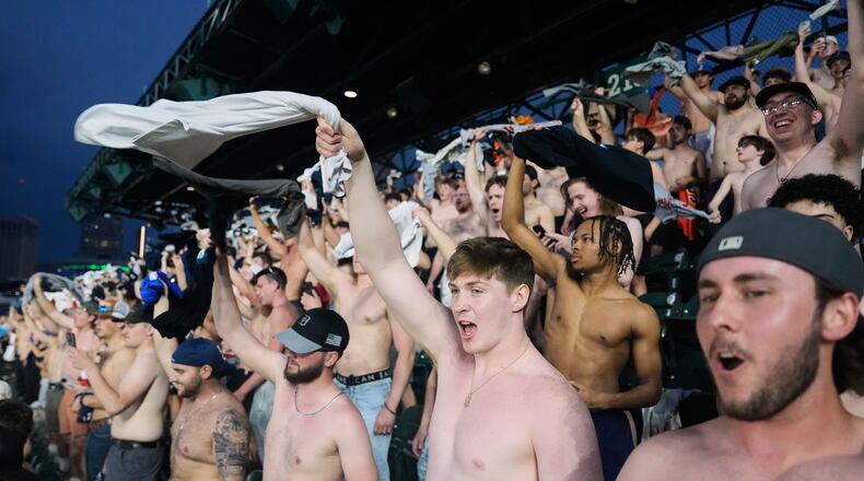 Fans cheer with their shirts off after heading to the upper deck outfield seating during the ninth inning of a baseball game between the Detroit Tigers and Cleveland Guardians Tuesday, May 19, 2026, in Detroit. (AP Photo/Paul Sancya)