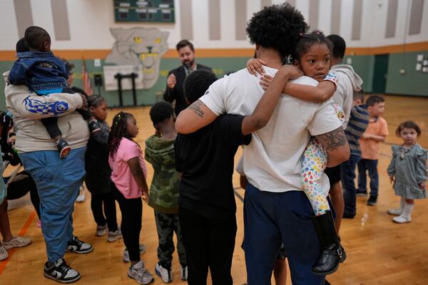 Ronald Lunsford, holds his childern Parker Scroggins, right, and Maleachi Yancey, standing left, as River Church Cincinnati pastor Cory Bowman, who is Vice President JD Vance's half brother and Cincinnati mayoral candidate, preaches during River Church Cincinnati Easter worship service in the Hays Porter Elementary School gym Sunday, April 20, 2025, in Cincinnati. (AP Photo/Carolyn Kaster)
