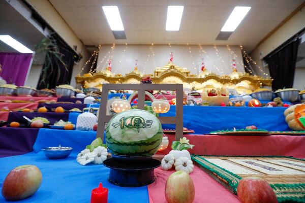 A watermelon carved with Pramukh Swami Maharaj's initials on a spinning display among the food offerings during the Diwali celebration at BAPS Shri Swaminarayan Mandir.