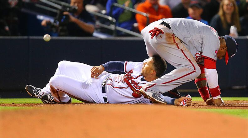 Braves shortsop Andrelton Simmons slides under the Nationals' Yunel Escobar safely at third base, advancing from first base on a wild pickoff attempt during the fifth inning. Escobar was injured on the play and left the game.