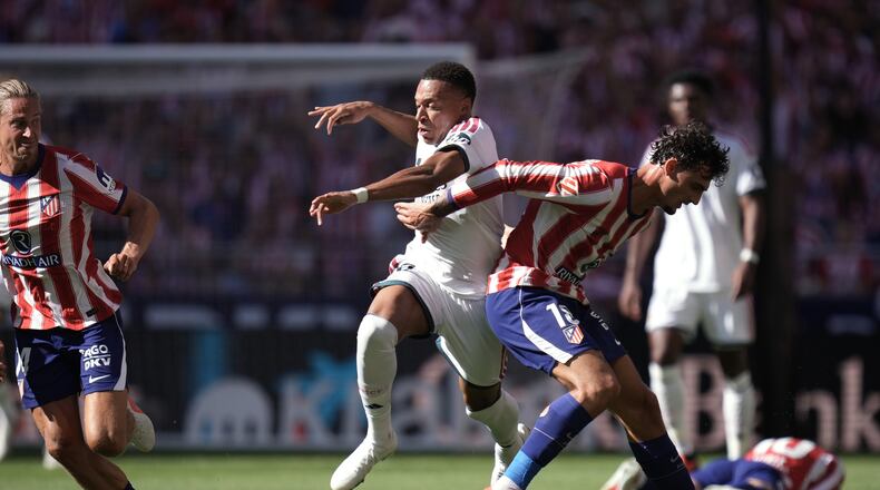 Real Madrid's Kylian Mbappe tries to get past Atletico Madrid's Marc Pubill, right, and Marcos Llorente during a Spanish La Liga soccer match between Atletico Madrid and Real Madrid in Madrid, Sunday, Sept. 20, 2026. (AP Photo/Bernat Armangue)