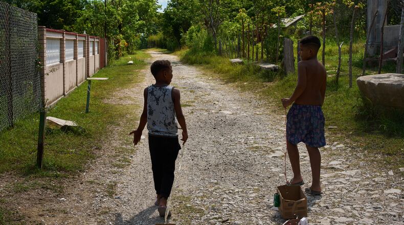 Children drag toys made from cardboard boxes as they walk in Minas, in Cuba's Havana province, Monday, Aug. 31, 2026. (AP Photo/Ramon Espinosa)