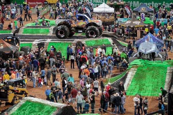 Fans wander around the field getting autographs from the drivers before the start of the Monster Jam in the Mercedes-Benz Stadium In Atlanta on Sunday, February 25, 2018. It takes 48 hours to lay down plywood over the football field and an additional 26 hours to bring in the dirt and build the track for the two-day event.  STEVE SCHAEFER / SPECIAL TO THE AJC