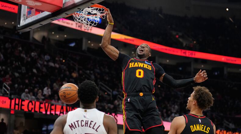 Atlanta Hawks forward Jonathan Kuminga (0) dunks in front of Cleveland Cavaliers guard Donovan Mitchell (45) and teammate Dyson Daniels (5) in the second half of an NBA basketball game in Cleveland, Wednesday, April 8, 2026. (AP Photo/Sue Ogrocki)