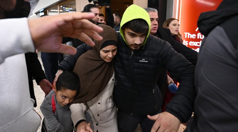 A group of supporters surround a woman with alleged ties to the Islamic State as she arrives with a child at Melbourne international Airport, in Melbourne, Australia, Thursday, May 7, 2026. (Joel Carrett/AAP Image via AP)