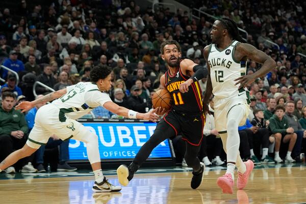 Atlanta Hawks' Trae Young (11) drives to the basket between Milwaukee Bucks' Taurean Prince (12) and Ryan Rollins during the first half of an NBA basketball game, Sunday, March 30, 2025, in Milwaukee. (AP Photo/Aaron Gash)