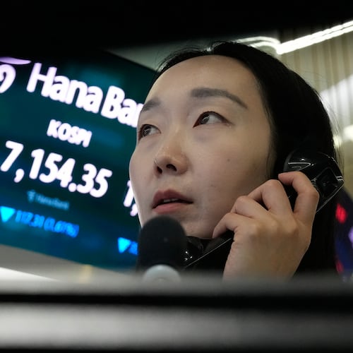 A currency trader talks on the phone near a screen showing the Korea Composite Stock Price Index (KOSPI) and the foreign exchange rate between U.S. dollar and South Korean won, left, at the foreign exchange dealing room of the Hana Bank headquarters in Seoul, South Korea, Wednesday, May 20, 2026. (AP Photo/Ahn Young-joon)