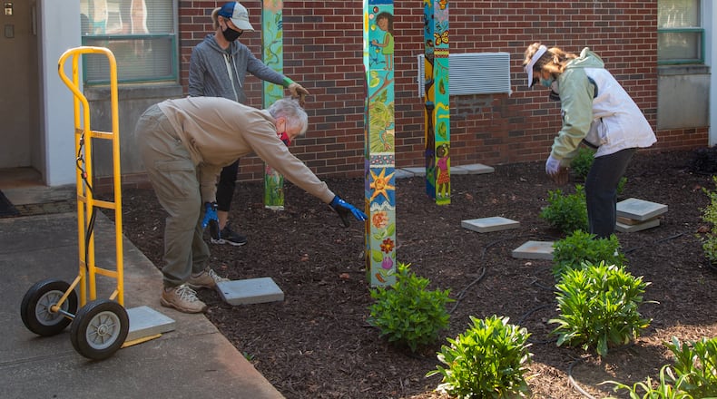 Co-chair Carolyn Chandler (clockwise from bottom left), Jennifer Houpt and Carolyn Adams place stepping stones around three hand-painted totem poles in the new garden area in front of Avondale Elementary School which also features a lending library. The Avondale Estates Garden Club and the Avon Garden Club worked together on the project.
PHIL SKINNER FOR THE ATLANTA JOURNAL-CONSTITUTION.