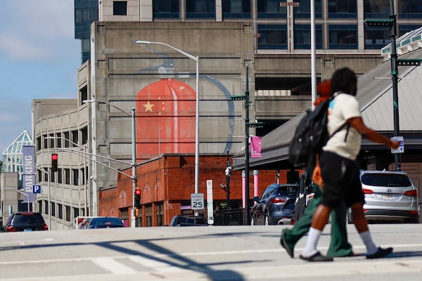 People cross Pryor Street at the intersection with Wall Street in downtown Atlanta, where a large mural of a fire extinguisher with the Chinese flag is displayed. The mural is by Escif, a Spanish street artist. (Miguel Martinez/AJC)