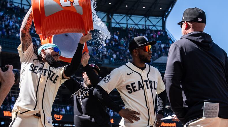 Seattle Mariners' J.P. Crawford, left, douses Victor Robles, second from right, after a baseball game against the Arizona Diamondbacks, Sunday, May 31, 2026, in Seattle. (AP Photo/Stephen Brashear)