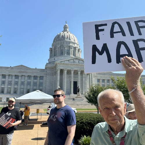 This photo taken with a smartphone shows Steve Perry, of Kansas City, holding a sign in opposition to Missouri’s congressional redistricting plan on Wednesday, Sept. 2, 2026, outside the state Capitol, in Jefferson City, Mo. (AP Photo/David A. Lieb)